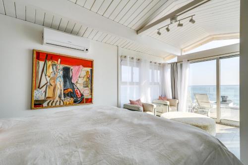 a bedroom with a large bed with a painting on the wall at Beachfront Malibu Apartment with Ocean-View Balcony in Malibu