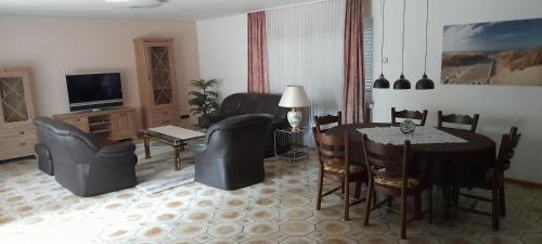 a living room with a table and chairs and a television at Ferienwohnung Aue Deußen in Erftstadt