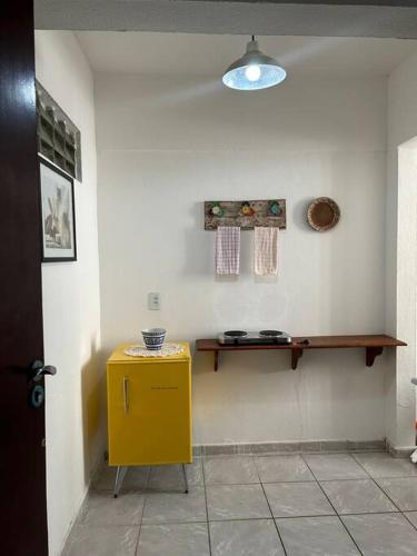 a room with a yellow table and a shelf on the wall at Apartamento a beira-mar Natal in Natal