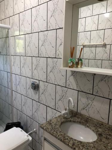 a white tiled bathroom with a sink and a mirror at Casa vermelha, sitio pousada vô maneca in Timbó