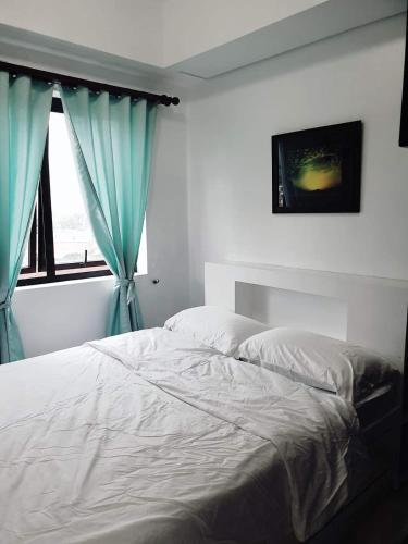 Studio Unit Persimmon Condominium في مدينة سيبو: غرفة نوم بسرير والستائر الزرقاء ونافذة