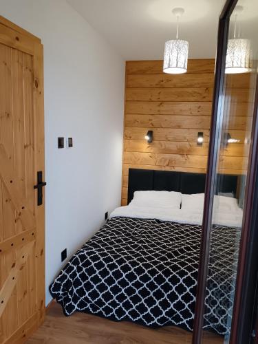 a bedroom with a bed with a wooden wall at Raj nad Narwią in Zatory