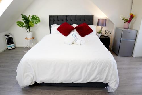 een slaapkamer met een groot wit bed met rode kussens bij 32GC Dreams Unlimited - Heathrow Studio Flat w free on-street parking in Staines upon Thames