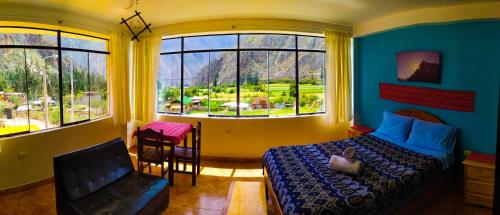 a bedroom with a bed and a chair and windows at Casa Samay Mountain View in Ollantaytambo