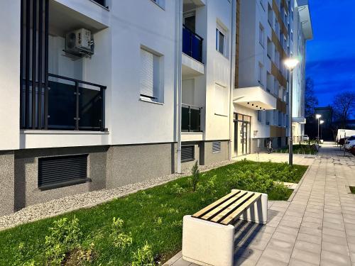 a bench sitting in the grass next to a building at SunShine Apartman CityBlock in Banja Luka