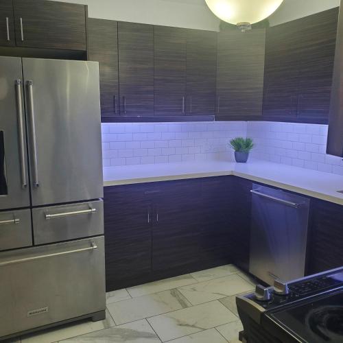 a kitchen with wooden cabinets and a stainless steel refrigerator at beautiful 2 level bungalow in a posh neighborhood. in Toronto