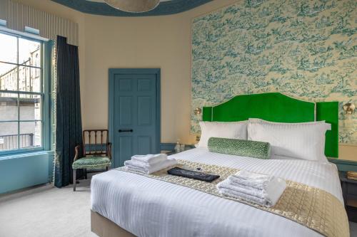 a bedroom with a large bed with a green headboard at Eleven Stafford Street Townhouse in Edinburgh