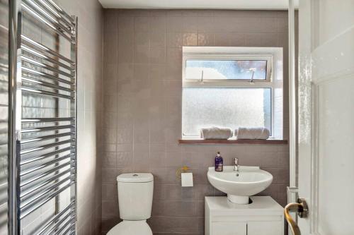 baño con aseo y lavabo y ventana en Beautiful 5 Bedroom Free Parking Semi-Detached house Aylesbury, en Buckinghamshire