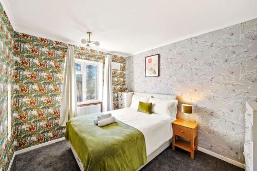 a bedroom with a white bed and floral wallpaper at Beautiful 5 Bedroom Free Parking Semi-Detached house Aylesbury in Buckinghamshire