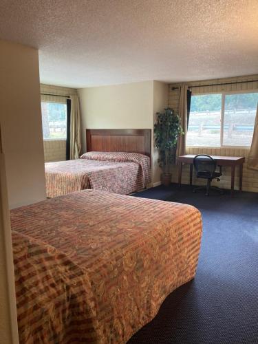 Una habitación de hotel con dos camas y un escritorio. en Travelodge by Wyndham Canyonville, en Canyonville
