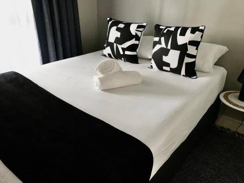 Una cama blanca y negra con dos toallas. en Apartment in Sandton, Rivonia en Johannesburgo