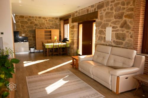 sala de estar con sofá y pared de piedra en La Tahona, en Fermoselle