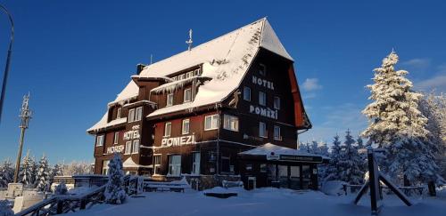 a large building with snow on it in the snow at Hotel a restaurace Pomezí in Cínovec