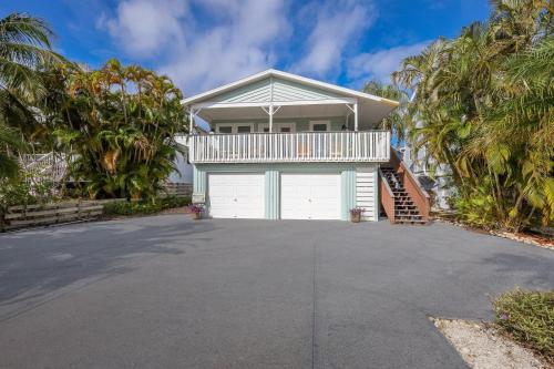 a house with a white garage and palm trees at Canario Cottage Home in Anna Maria