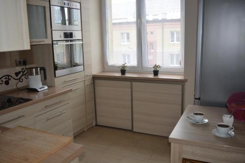 una cocina con 2 ventanas y una mesa. en Apartament Hel Zacisze, en Hel