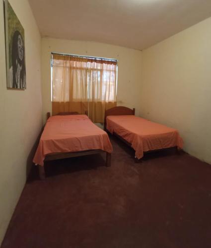 two beds in a room with a window at Casa hospedaje cora in Barrio Bellavista