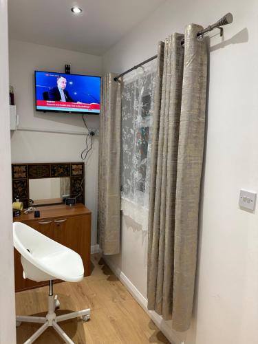 a room with a white chair and a television on a wall at Double Room With Free WiFi Keedonwood Road in Bromley
