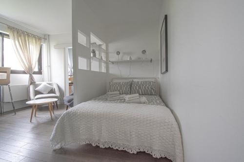 een witte slaapkamer met een bed en een stoel bij La Charmille du Lac in Créteil