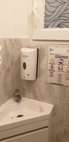 a bathroom with a sink and a soap dispenser on the wall at Calaisis room bed in Calais