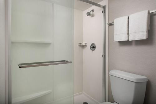 a bathroom with a shower with a toilet and towels at Courtyard by Marriott Dothan in Dothan