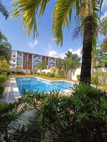 a swimming pool with a palm tree in front of a building at Amenadiel & CC - Imus Staycation in Imus