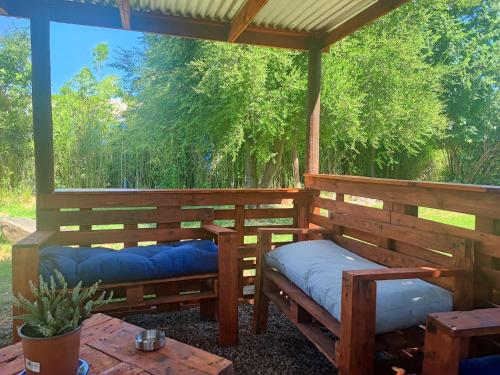 a porch with benches and a table and trees at Hostal Fernanda in Santa Cruz
