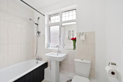 Dunstable 3 bedroom house with Free Parking في دانستابل: حمام أبيض مع حوض ومرحاض وحوض استحمام