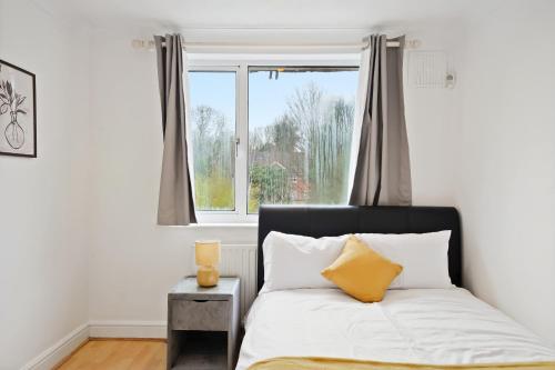 Dunstable 3 bedroom house with Free Parking في دانستابل: غرفة نوم بسرير ونافذة
