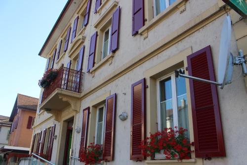 a building with purple shutters and flowers on the windows at Hôtel de la Gare in Yvonand