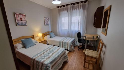 Zimmer mit 2 Betten und einem Schreibtisch mit Stuhl in der Unterkunft Soleado piso 4 habit a pie de playa Sanxenxo in Sanxenxo