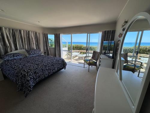 een slaapkamer met een bed en uitzicht op de oceaan bij Matarangi Beachfront - Matarangi Holiday Home in Matarangi