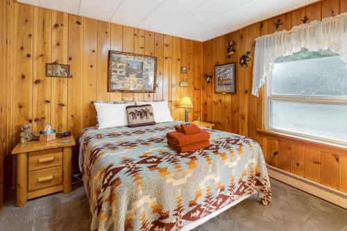 une chambre avec un lit avec des murs en bois et une fenêtre dans l'établissement Rosebud Cottage, à Joseph