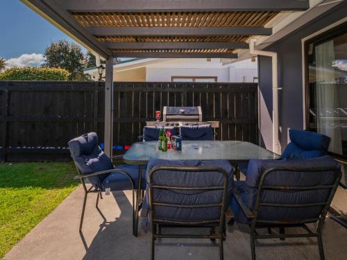 a patio with a table and chairs and a fence at Walk to the Water - Whangamata Holiday Home in Whangamata