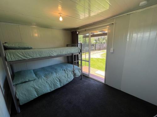 a room with two bunk beds and a sliding glass door at Walk to the Water - Whangamata Holiday Home in Whangamata