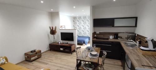 a living room with a kitchen and a table with a table at Tout confort. Appartement 2 pers. centre-ville in Le Creusot
