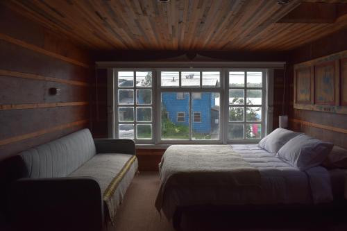 a bedroom with a bed and a couch and a window at Estación Hostel in Castro