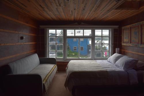 Un dormitorio con una cama y un sofá y una ventana. en Estación Hostel, en Castro