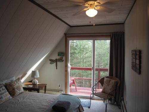 1 dormitorio con cama, ventana y silla en Cub Hill Chalet - Private Lakefront With Spa!, en Kalkaska