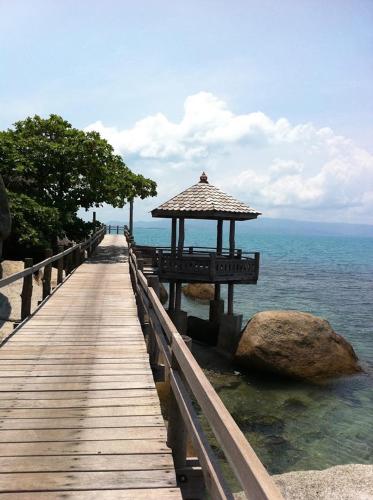 a wooden boardwalk with a gazebo on the water at Lighthouse Bungalows in Haad Rin