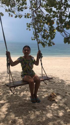 a woman sitting on a swing on the beach at Lighthouse Bungalows in Haad Rin