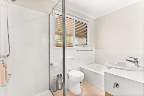 Un baño blanco con inodoro y lavabo. en Amongst the Palms Inverloch, en Inverloch