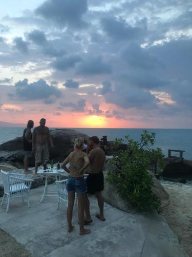 a group of people standing around a table on the beach at Lighthouse Bungalows in Haad Rin