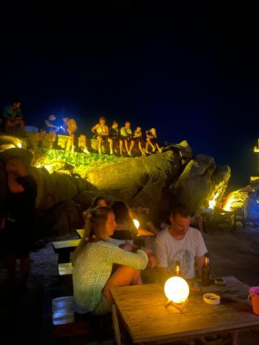 a group of people sitting at tables at the beach at night at Lighthouse Bungalows in Haad Rin