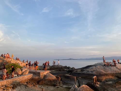 a group of people standing on rocks near the water at Lighthouse Bungalows in Haad Rin
