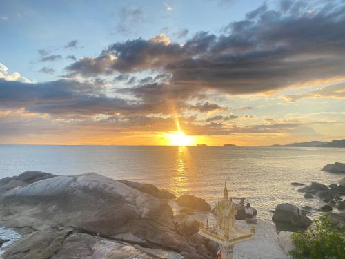 a sunset on the shore of a body of water at Lighthouse Bungalows in Haad Rin