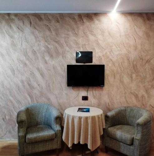 two chairs and a table with a tv on a wall at FUN ROOMS SOBE PRENOĆIŠTE in Borča