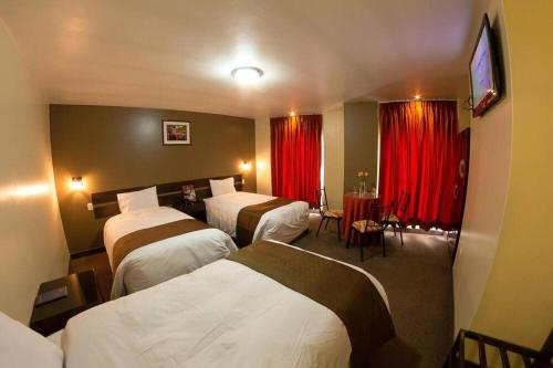 um quarto de hotel com três camas e cortinas vermelhas em UTASA VILLAREAL Inn em Puno