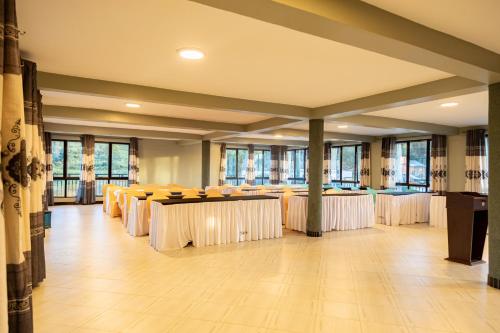 un salón de banquetes con mesas, sillas y ventanas en Bwizi Resort and Gardens, en Kanyigiri
