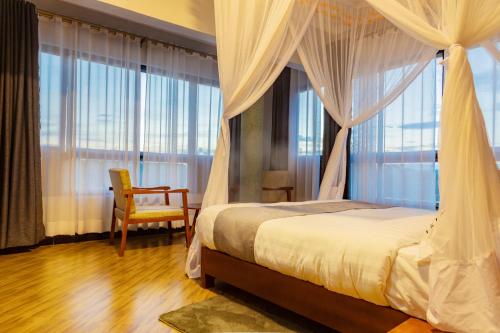 1 dormitorio con 1 cama, 1 silla y ventanas en Bwizi Resort and Gardens, en Kanyigiri