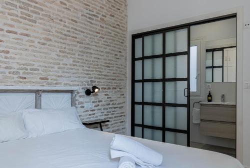 a bedroom with a white bed and a brick wall at Sepúlveda, tranquilo y con piscina by OUTIN in Seville